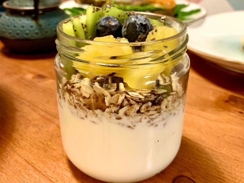 vaso de yoghurt natural con granola y trozos de fruta